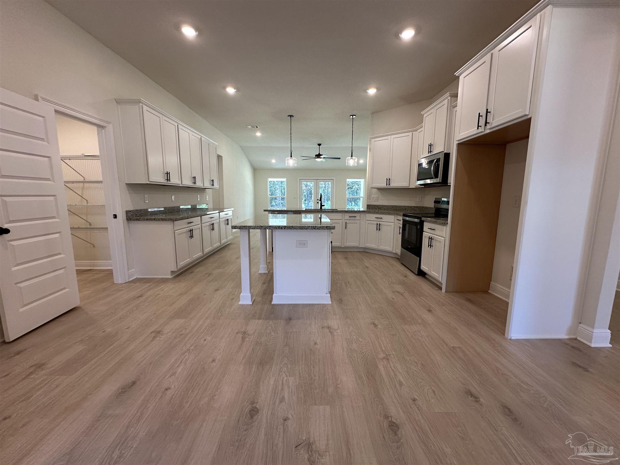 5223 Wahoo Road Milton, FL 32583 - Photo 10 of 26 a kitchen with stainless steel appliances kitchen island wooden cabinets and a stove top oven