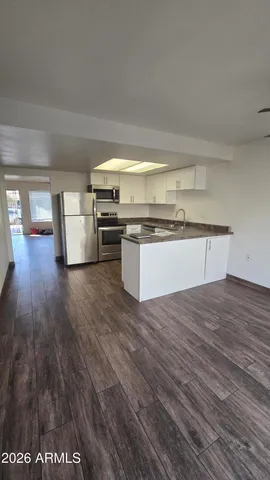 a kitchen with stainless steel appliances wooden floors and a view of living room