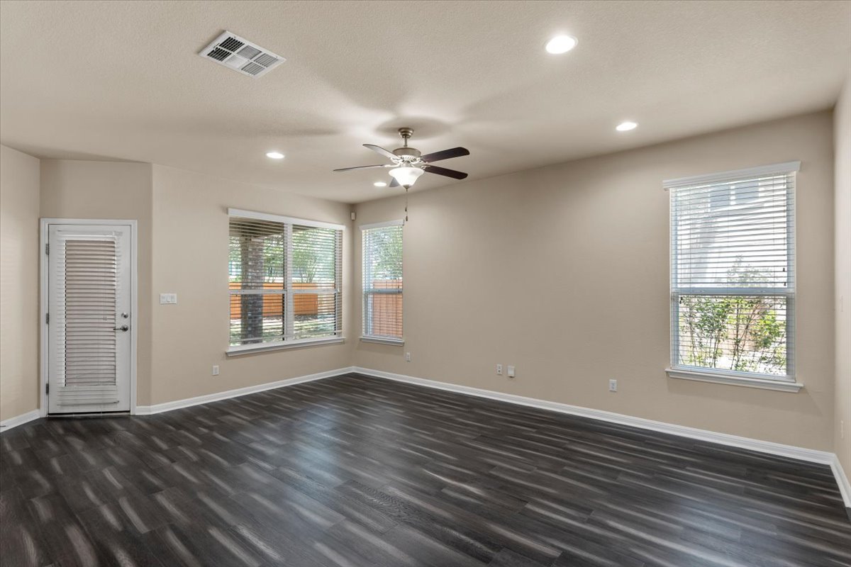 3451 Mayfield Ranch Boulevard, Unit 311 Round Rock, TX 78681 - Photo 5 of 40 Spacious room featuring dark wood-finish flooring, multiple windows with blinds, a ceiling fan, recessed lighting, and a door with louvered glass