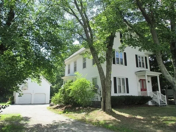a view of a white house with a big yard and potted plants and large trees
