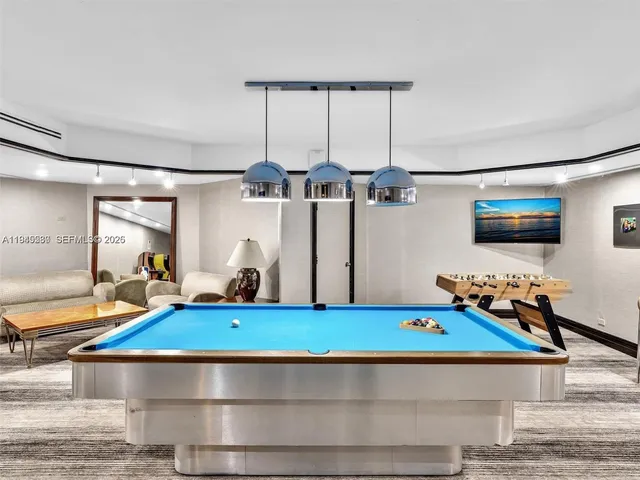 a room with wooden floor pool table and windows