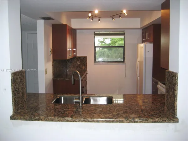 a kitchen with kitchen island granite countertop a refrigerator a stove and a sink