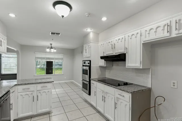 a kitchen with granite countertop a sink a stove and cabinets