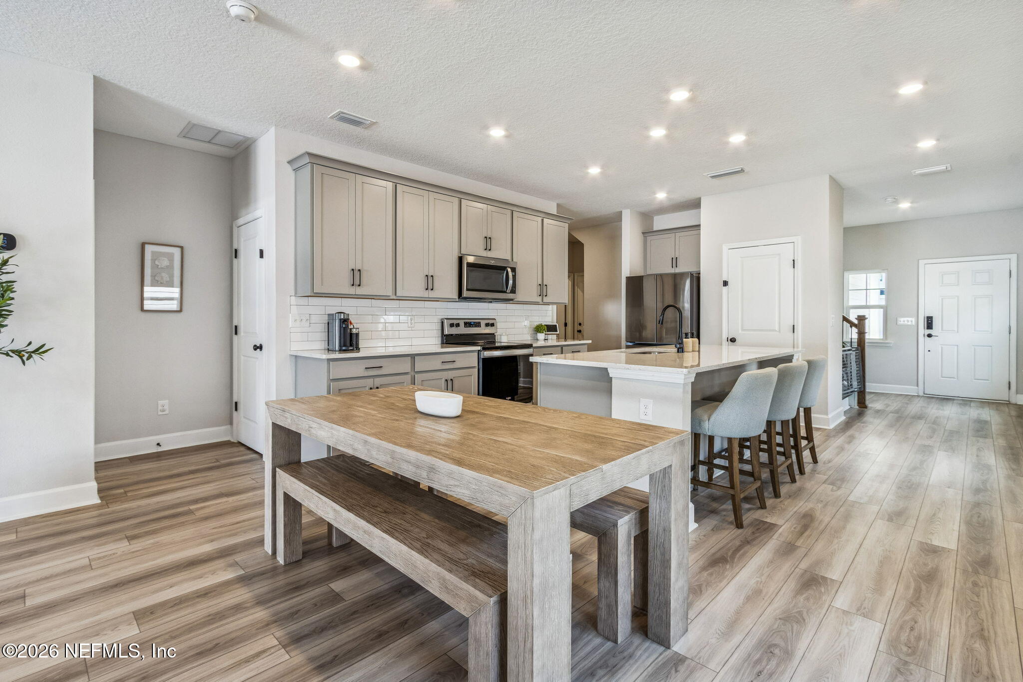 95057 Terris Way Fernandina Beach, FL 32034 - Photo 11 of 43 a kitchen with stainless steel appliances granite countertop a table chairs wooden floors and a view of living room