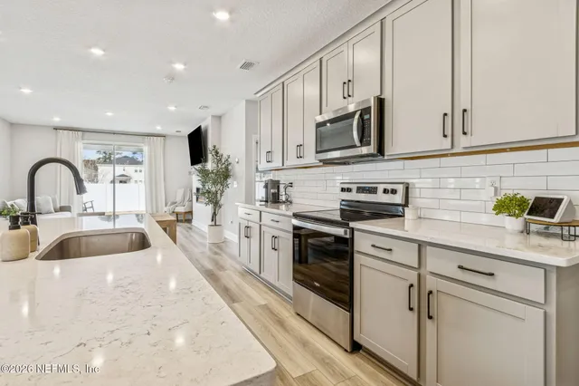 a kitchen with stainless steel appliances granite countertop a sink a stove and a refrigerator