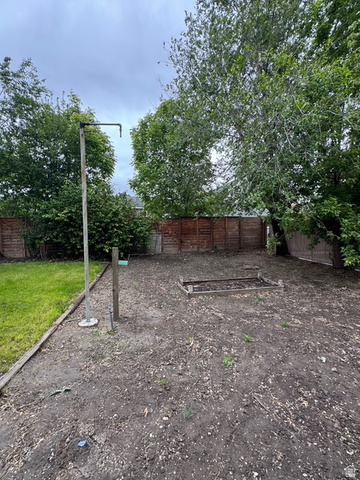 189 West Center Street Midvale, UT 84047 - Photo 52 of 64 Spacious backyard area featuring a wood fence perimeter, a designated garden bed, and mature trees providing natural shading