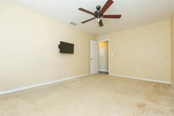 an empty room with a ceiling fan and carpet
