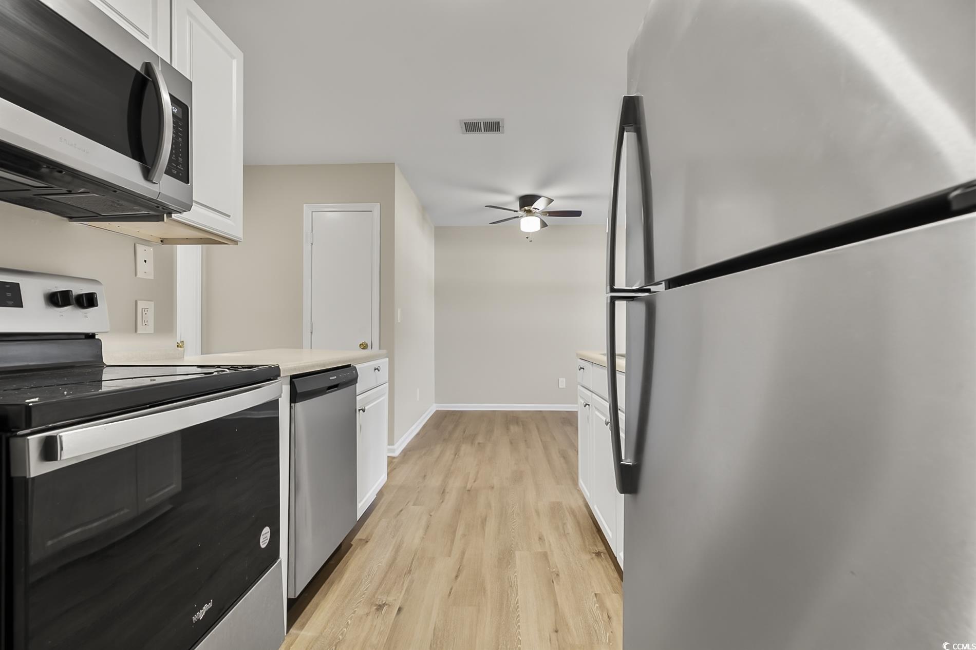 4150 Horseshoe Road North, Unit 38 Little River, SC 29566 - Photo 11 of 29 Kitchen with appliances with stainless steel finishes, light countertops, white cabinetry, and light wood finished floors