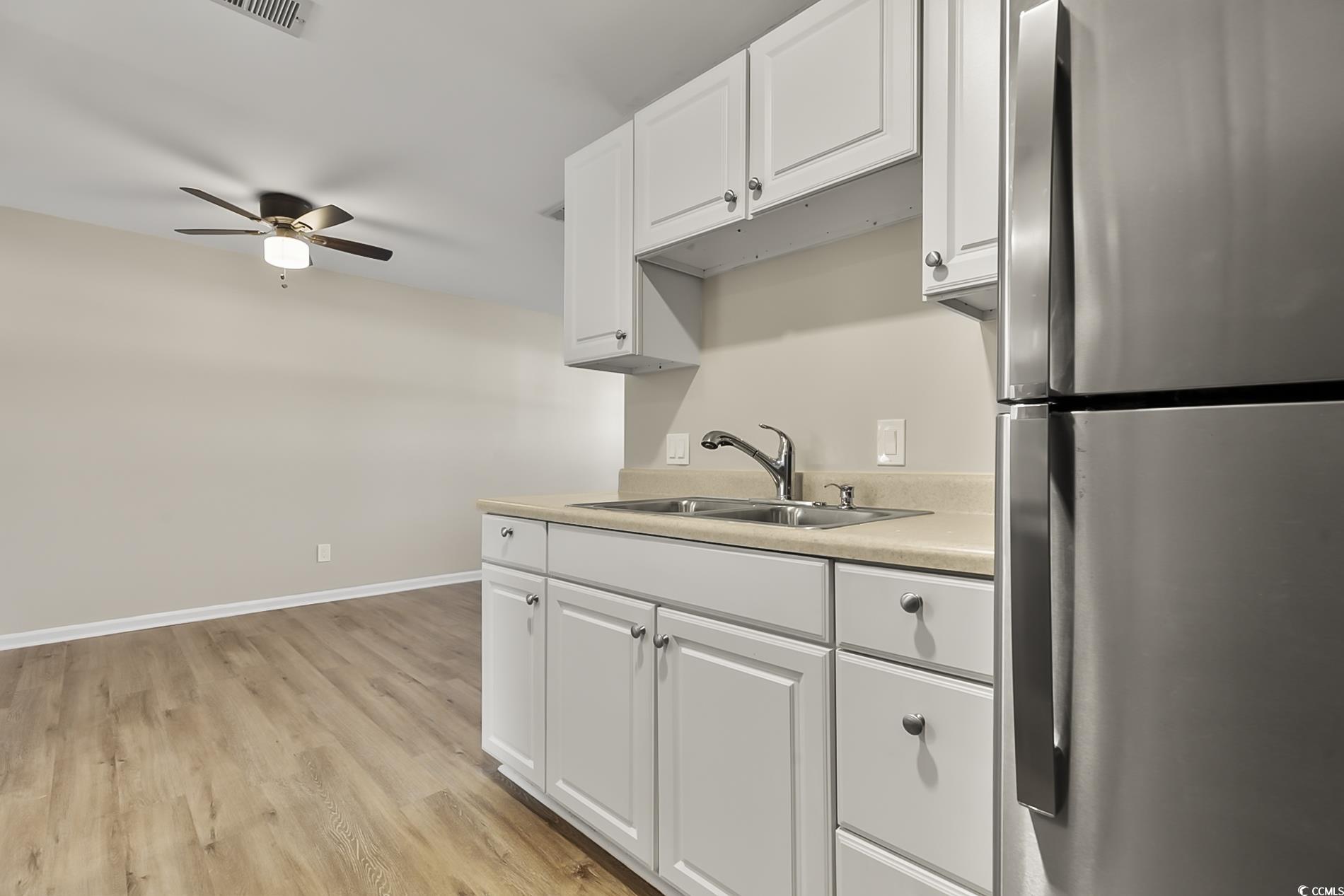 4150 Horseshoe Road North, Unit 38 Little River, SC 29566 - Photo 12 of 29 Kitchen featuring freestanding refrigerator, light countertops, white cabinets, light wood-style floors, and a ceiling fan