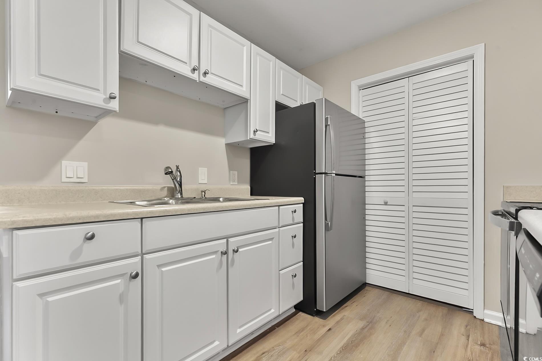 4150 Horseshoe Road North, Unit 38 Little River, SC 29566 - Photo 10 of 29 Kitchen featuring light countertops, white cabinetry, light wood-style floors, freestanding refrigerator, and black stove