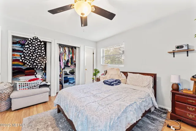 a bedroom with a bed and a walk in closet with wooden floor