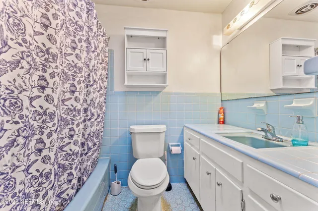 a bathroom with a granite countertop toilet sink and mirror