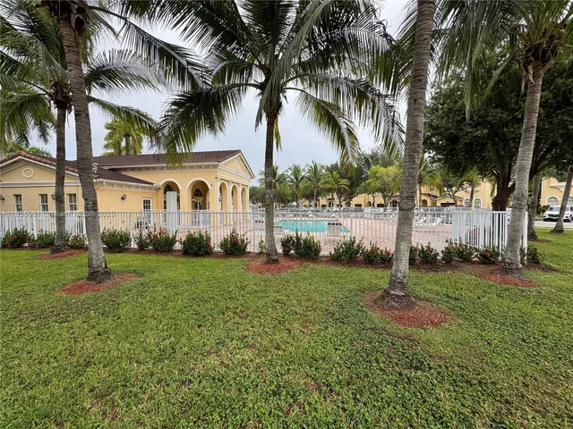 a view of a house with a yard and palm trees