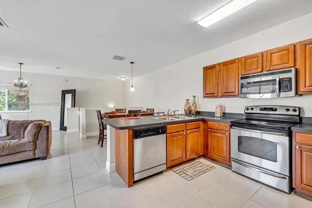 a kitchen with stainless steel appliances granite countertop a stove top oven a sink dishwasher a dining table and chairs with wooden floor