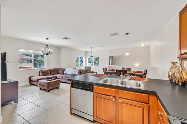 a living room with furniture kitchen view and a chandelier