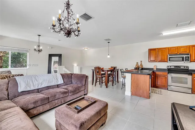 a living room with furniture kitchen view and a chandelier