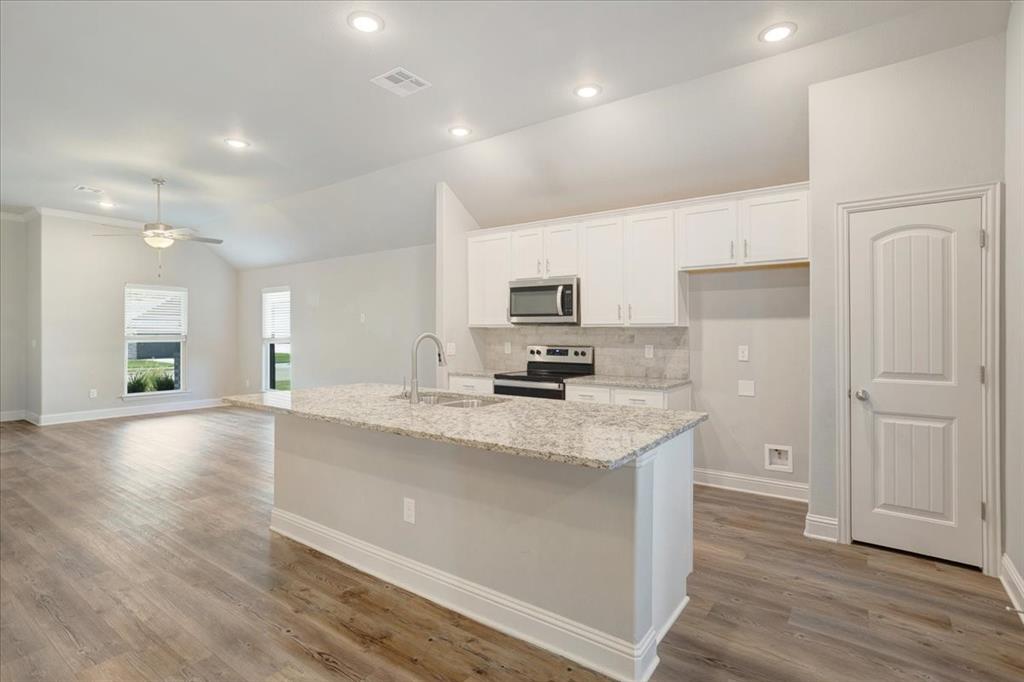 2111 Wyldewood Way Sherman, TX 75092 - Photo 11 of 33 a large kitchen with stainless steel appliances granite countertop a lot of counter space and wooden floors