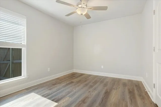 an empty room with a window and a ceiling fan