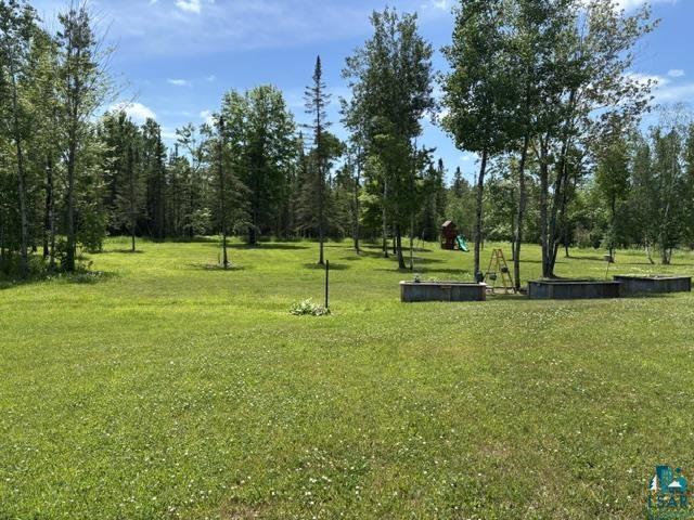 3454 Anderson Road Hibbing, MN 55746 - Photo 31 of 31 Expansive green lawn surrounded by mature trees, featuring multiple raised garden beds