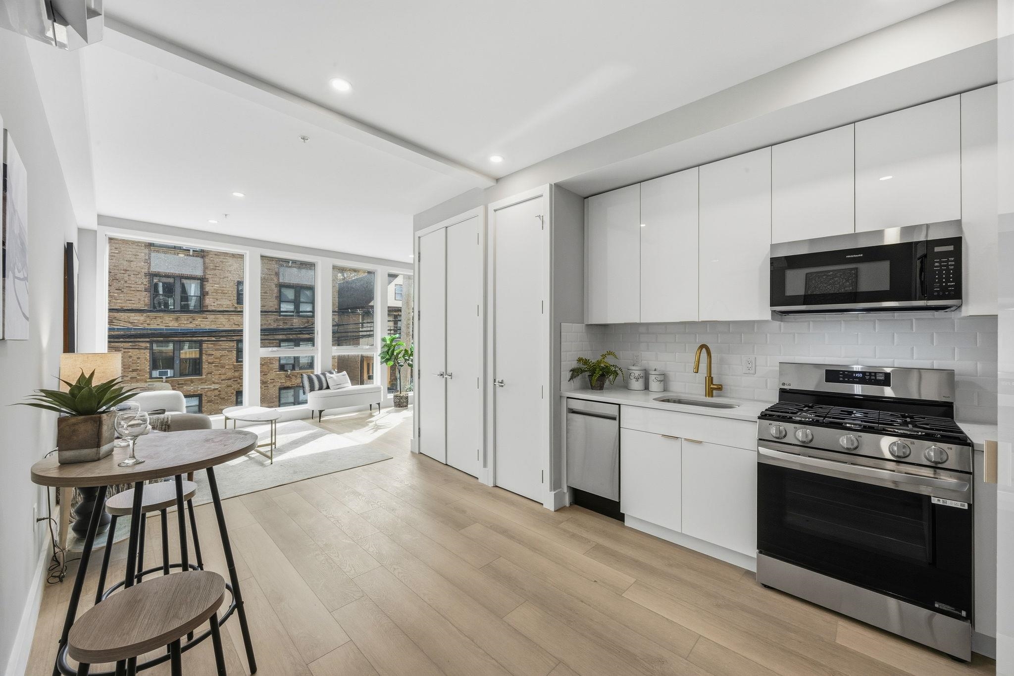 77 Van Reypen Street, Unit 3 Jersey City, NJ 07306 - Photo 2 of 23 a kitchen with stainless steel appliances a stove a sink a microwave a dining table and chairs
