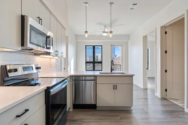 a kitchen with stainless steel appliances granite countertop a sink a stove and a wooden floors