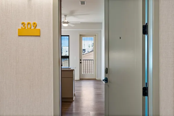 a view of a hallway with wooden floor and a bathroom