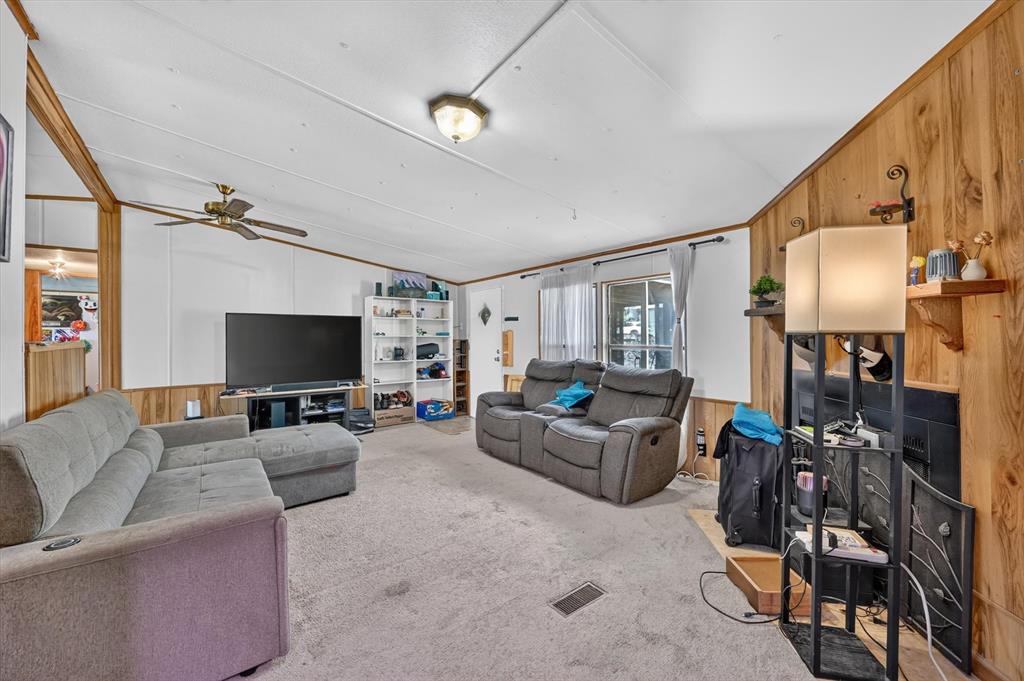 736 Little Joe Road Sanger, TX 76266 - Photo 4 of 17 Carpeted living area featuring wood-paneled walls and a built-in shelf