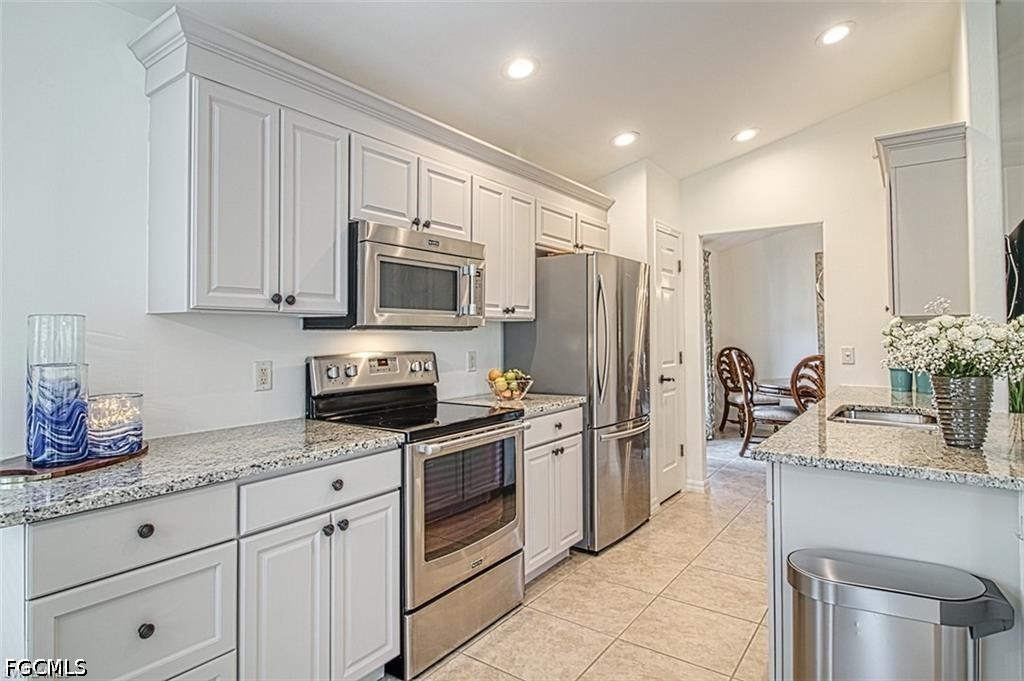 10072 Oakhurst Way Fort Myers, FL 33913 - Photo 8 of 26 a kitchen with granite countertop a sink stainless steel appliances and white cabinets