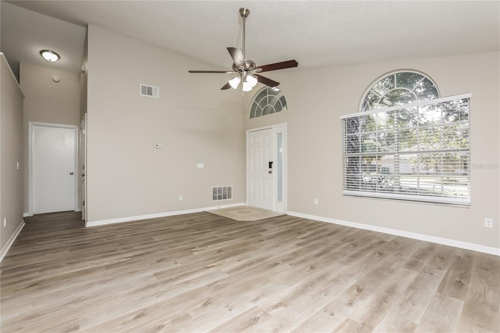 3007 East Beaumont Lane Eustis, FL 32726 - Photo 2 of 16 an empty room with wooden floor chandelier fan and windows