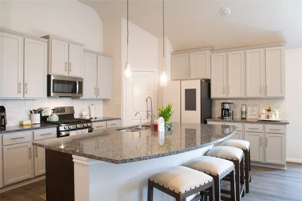 a kitchen with kitchen island granite countertop a sink counter top space appliances and cabinets