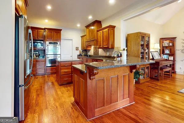 a kitchen with stainless steel appliances granite countertop a stove top oven a sink dishwasher and cabinets with wooden floor