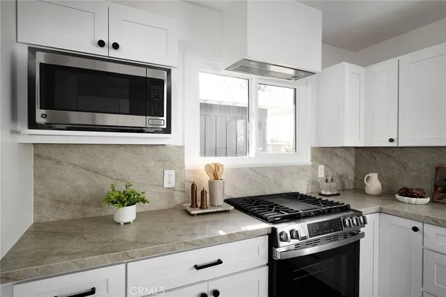 a kitchen with granite countertop stainless steel appliances a stove a microwave and cabinets