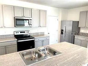 a kitchen with granite countertop a sink stove and refrigerator
