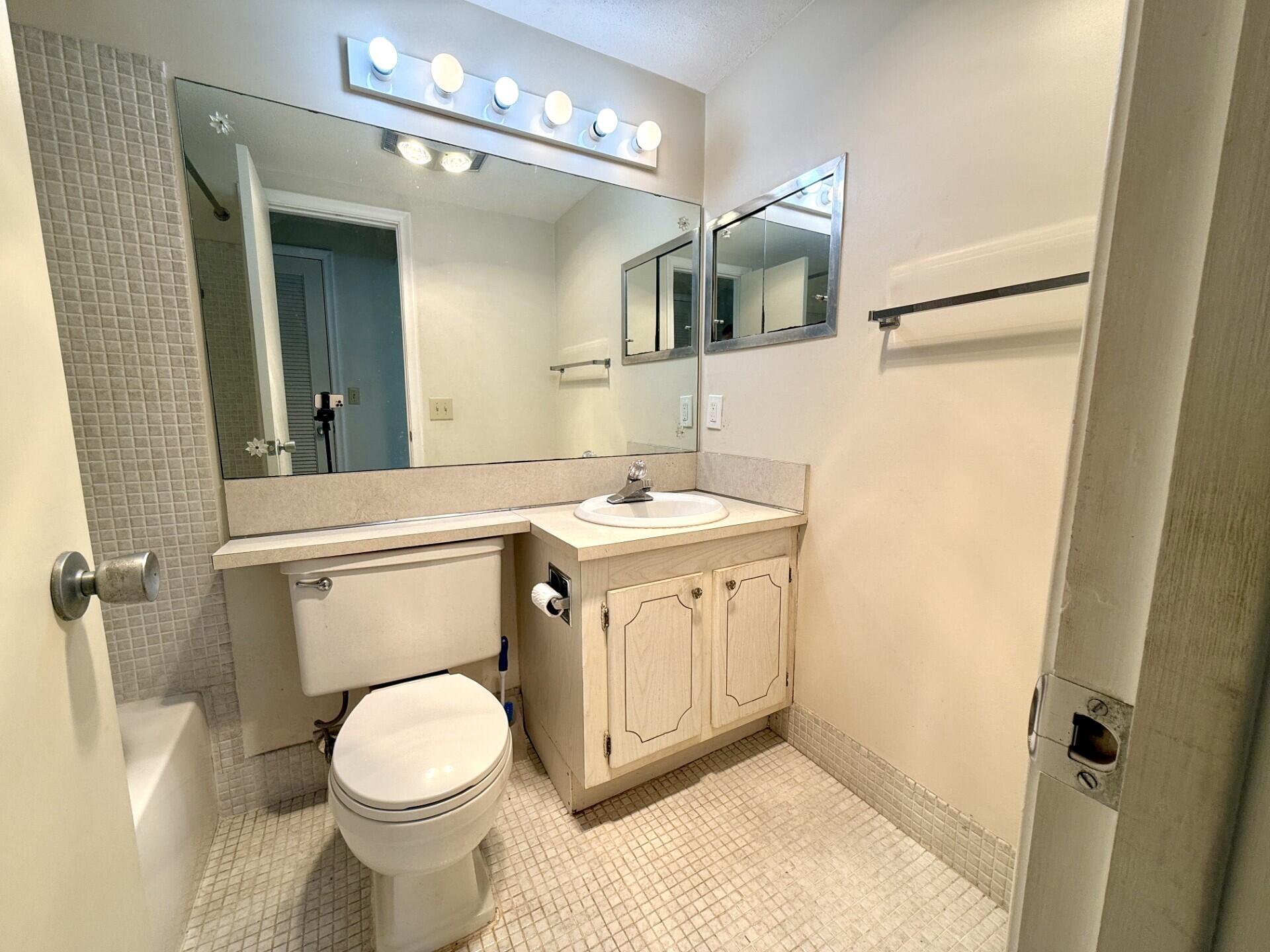 69 Norwich C West Palm Beach, FL 33417 - Photo 10 of 17 a bathroom with a sink a toilet and mirror