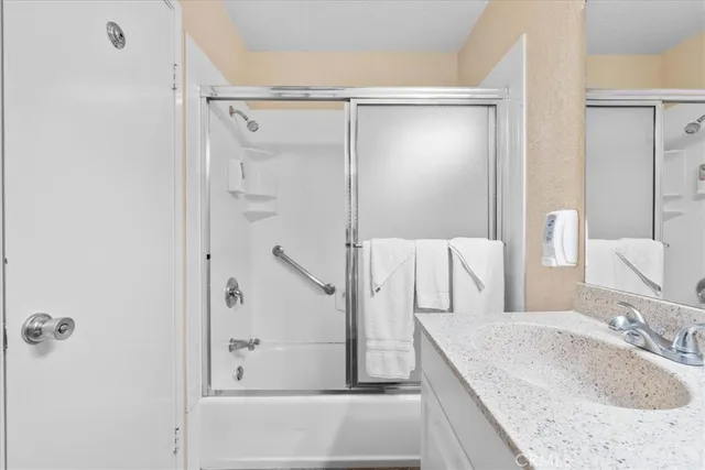 a bathroom with a granite countertop sink mirror and shower
