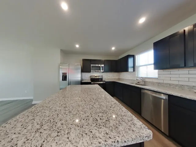 a large kitchen with stainless steel appliances kitchen island a large counter top and a sink