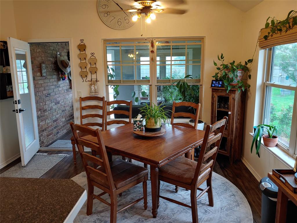 836 Airport Road Reno, TX 75462 - Photo 9 of 30 Dining area featuring wood-finish flooring, a large window overlooking the exterior, and a ceiling fan with integrated lighting