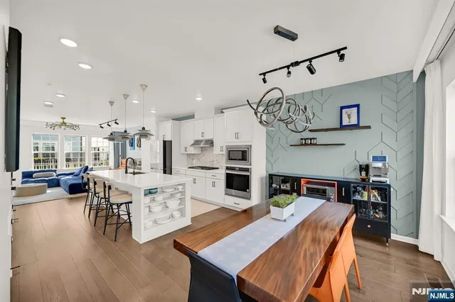 a view of a dining room and livingroom with furniture wooden floor a chandelier