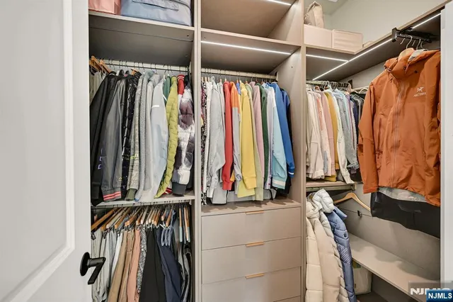 a view of walk in closet with clothes and shoes