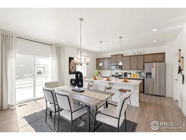 a dining room with stainless steel appliances kitchen island granite countertop a dining table chairs and refrigerator