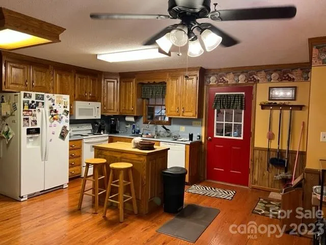 a kitchen with stainless steel appliances granite countertop a stove top oven a refrigerator a dining table and chairs with wooden floor