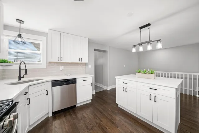 a kitchen with a sink dishwasher and white cabinets with wooden floor