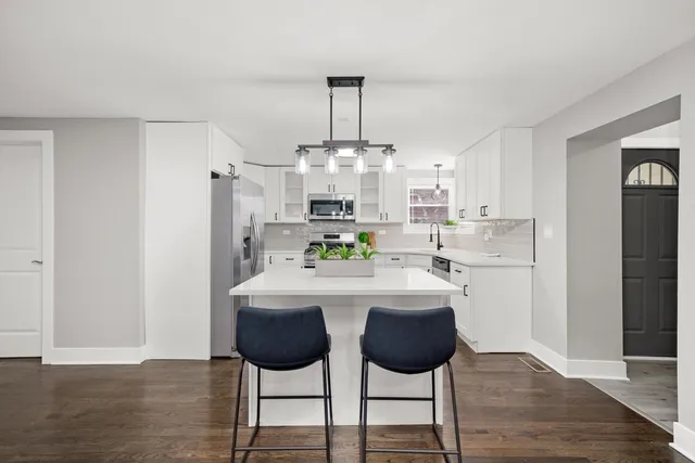 a kitchen with stainless steel appliances a dining table chairs and refrigerator