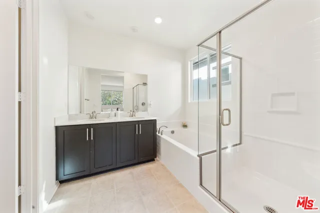 a spacious bathroom with a double vanity sink a mirror and shower