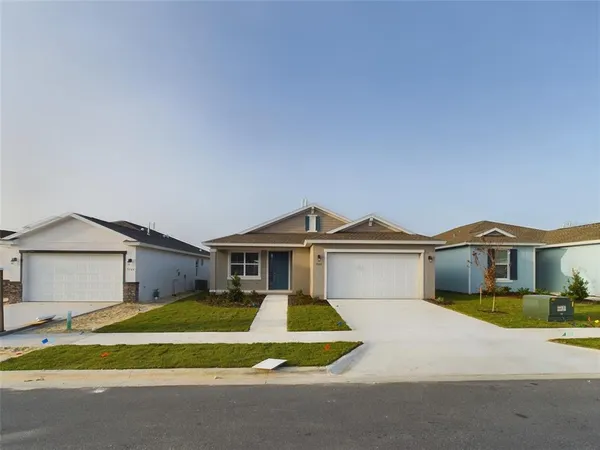 a view of a white house with a large windows and a yard and large trees
