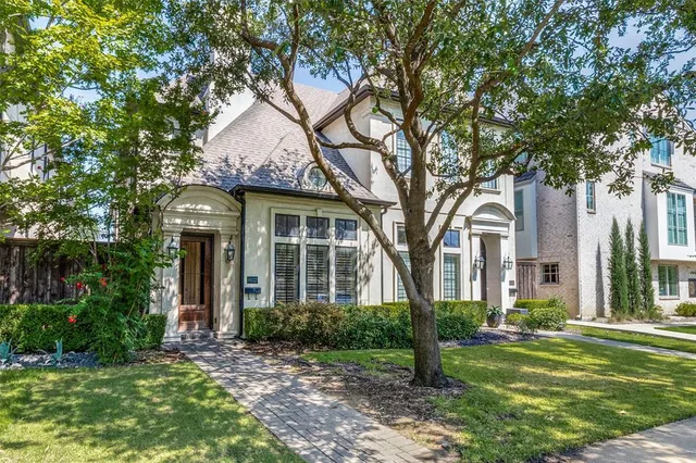 a front view of a house with a garden and trees