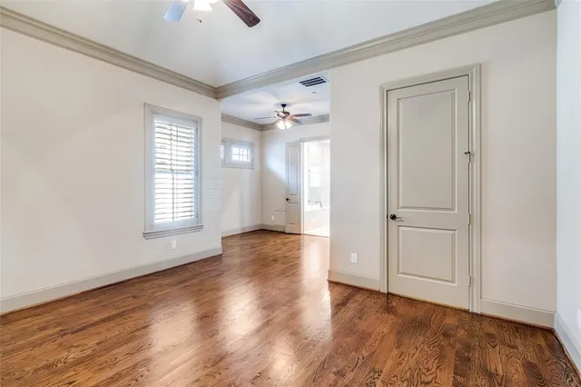 an empty room with wooden floor cabinet and windows