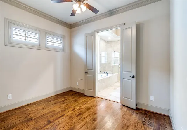an empty room with wooden floor cabinet and windows