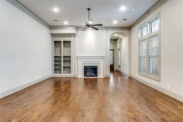 a view of an empty room with wooden floor fireplace and a window