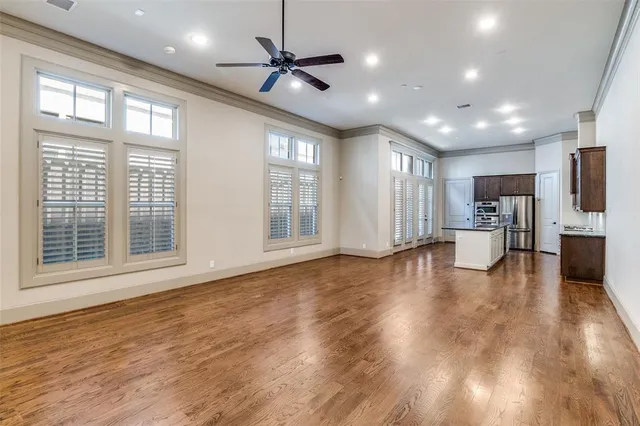 a view of an empty room with wooden floor and a kitchen